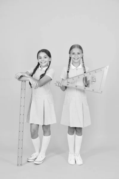 Crianças inteligentes na aula de tronco. As raparigas adoram geometria. Velha escola. educação moderna. amigos felizes em uniforme retro. moda de criança vintage. de volta à escola. meninas pequenas segurar ferramentas de matemática. Disciplinas STEM — Fotografia de Stock