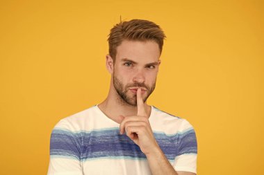 Ağzını kapat. Sır olarak saklamaya çalışıyorum. Sarı arka planda sessiz hareketler yapan gizli ajan ya da ajan. Yakışıklı bir adam ağzını kapalı tutamıyor. Gizli bilgi ve çok gizli
