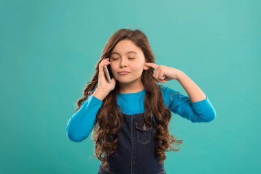 Düşük sesli. Mobil iletişim. Bilgi ve haberler. Modern bir alet. Yetiştirme ve geliştirme. Küçük kız cep telefonunu mavi arka planda arıyor. Şirin çocuk, akıllı telefonu tut. Mobil konuşma