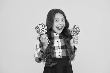 Şekerli mutlu çocuk. Okul beslenmesi. Kalori ve enerji. Zararlı gıda. Tatlılara deli oluyor. Şeker bağımlılığı. Tatlı şekerli mutlu çocuk. Lolipop tutan çocuk çocuk şeker sarı arka plan