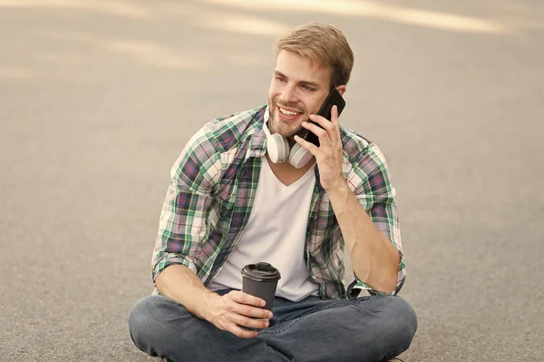 Llama a un amigo. Bienestar y salud. Tomando un café. El hombre se sienta en el suelo mientras bebe café. Relájate y recarga. Diviértete durante el descanso. Guy estudiante despreocupado disfrutar del café al aire libre. Balance de vida — Foto de Stock