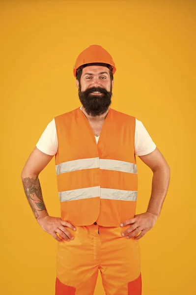 Завтра в здании. Бородатый мужчина улыбается в защитной рабочей одежде для строительной деятельности. Счастливый ремонт здания на желтом фоне. Строительство и строительство — стоковое фото