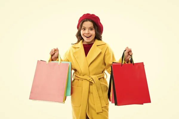 Torby są pełne. Szczęśliwy klient trzyma torby na zakupy. Małe dziecko uśmiecha się papierowymi torbami. Mała dziewczynka lubi sezonową wyprzedaż. Przewożenie wakacyjnych zakupów w kolorowych torbach. Jesienna sprzedaż — Zdjęcie stockowe