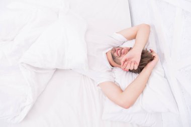 Beyaz yatak odasında uyuyan adam. Evde rahat bir hafta sonu. Rahatlama zamanı. Adam uykusuz bir gece geçirmiş. Erkek sağlığı konsepti. Barışseverlik kavramı. Yorgun adam yatakta uyuyor. Sabah erken kalktım.