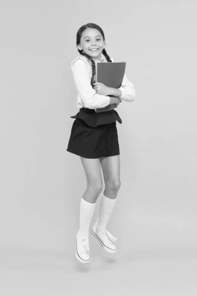 Aluno emocional. Entusiasmado por estudar. Criança feliz pulando em uniforme escolar. A divertir-me. Saltar e sentir-se livre. De volta ao conceito de escola. Menina de fundo amarelo. Escola menina gosta de estudar — Fotografia de Stock