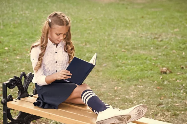 Czas na naukę. Uczę się na podwórku. Mądra uczennica. Student adorable dziecko w formalnym mundurze relaks na świeżym powietrzu. Uczennica czyta książkę. Mały geniusz. Uczennica relaksujący siedzieć na ławce z książki — Zdjęcie stockowe