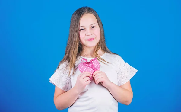 Happy valentines day. Small girl holding stuffed handmade heart for Valentines day. Little child with heart shaped decoration for valentines celebration. Valentines day gift