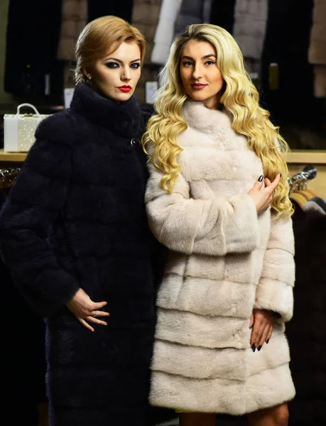 Friends in shop: ladies try expensive dark and white overcoats — Stock Photo, Image