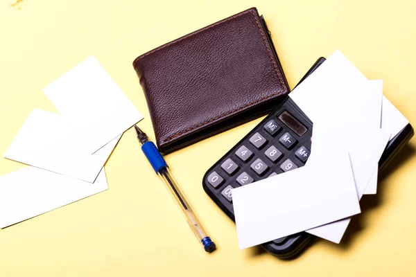 Leather wallet, calculator and cards with pen on yellow background. — Stock Photo, Image