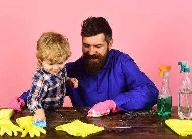 Oğlu ve babası pembe arka planda izole edilmiş spreylerin yanında..