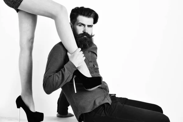 Bearded man with sexy female legs has serious face — Stock Photo, Image