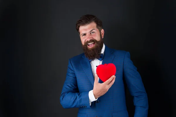 Saúde. Decoração do dia dos namorados. Homem de smoking com coração vermelho. Celebração de férias. conceito de amor. Dia Mundial do Coração. Um hipster barbudo brutal num fato formal. Homem de negócios de gravata borboleta. ataque cardíaco — Fotografia de Stock