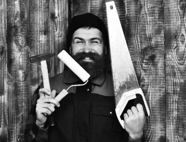 Costruttore barbuto in possesso di vari strumenti di costruzione con volto felice — Foto Stock