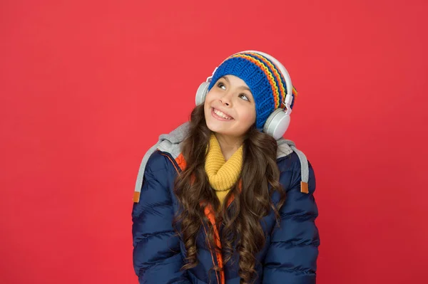 Musica per l'inverno. Bambino felice ascoltare musica sfondo rosso. La bambina indossa le cuffie suonando musica. Nuove tecnologie. La vita moderna. Divertimento e intrattenimento. Mi piace la mia musica forte — Foto Stock