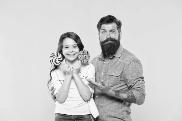 Kleine meid en vader hebben kleurrijke lolly. Zomer vibes. Een gelukkig gezin. Vrolijk over het dessert. snoepwinkel. Gelukkige jeugd. Dochter en vader eten snoep. Een bebaarde hipster is een goede vader. geluk — Stockfoto