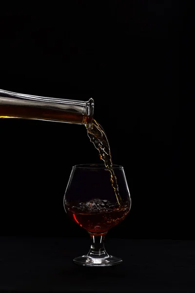 Whisky gegoten in laag glas op zwarte achtergrond. — Stockfoto