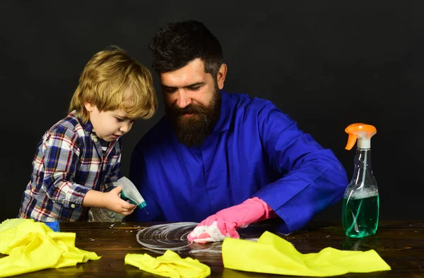 Kid and father with busy faces cleaning together with spray.