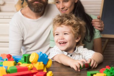 Ebeveynler, oğullarının bloklardan yapılmış binaları tutmasını seyrediyorlar..