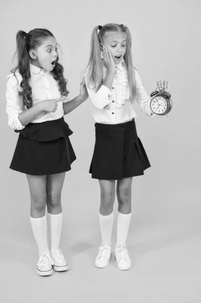 Tijd voor pauze en ontspanning. Het alarm gaat af. Tijd voor de lunch. Schoolrooster. Schoolmeisjes en wekker. Kinderen scholieren schattig formeel uniform outfit. Kinderen houden wekker tellen tijd — Stockfoto