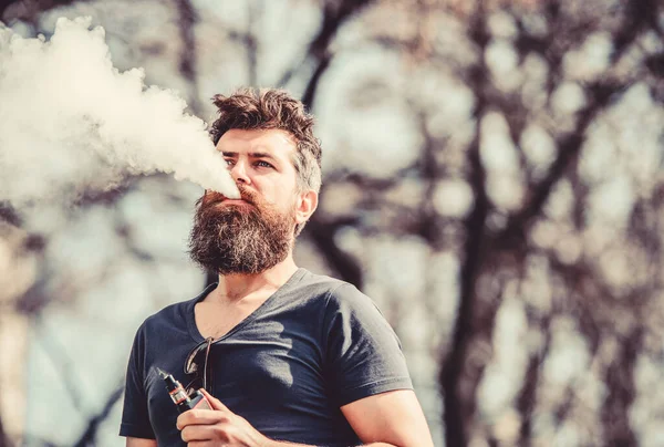 Concepto de alivio del estrés. Hombre barbudo fumando vapor. Fumar cigarrillo electrónico. Hombre barba larga relajado con hábito de fumar. El hombre con barba y bigote exhala humo. Nubes blancas de humo aromatizado —  Fotos de Stock