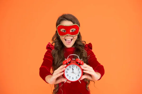 O momento certo é agora. Festa menina mostrar relógio hora. Criança pequena em máscara de carnaval segurar despertador. 12 oclock. Hora da meia-noite. Está na hora de celebrar. Celebração de férias. Natal e ano novo — Fotografia de Stock