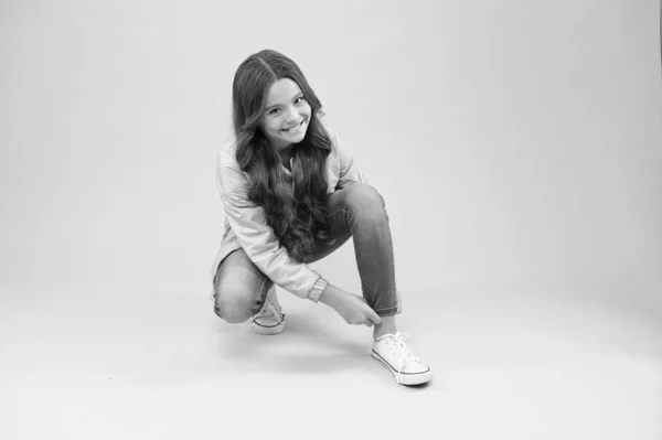 Adorable and stylish. Happy child fix jeans on pink background. Beauty look of little girl child. Fashion child smile in casual style. Cute small child smiling with long curly hair — ストック写真