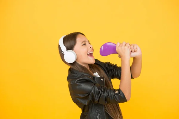 Een kind met een headset. klein meisje zingen favoriete lied. Stel je voor dat je popster bent. karaoke zingen. zangeres leren jas. Kinderen luisteren naar rockmuziek. schoolradio dj. hipster stedelijke stijl meisje — Stockfoto