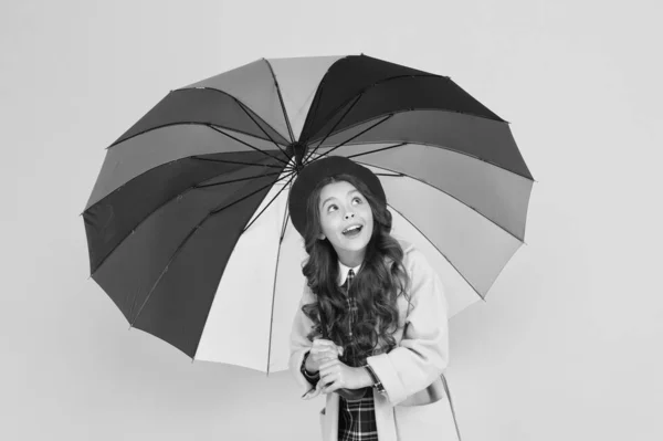 Якщо ви не хочете дощу, завжди носіть парасольку. Мила дівчинка перевіряє дощ на жовтому тлі. Чарівна маленька дитина тримає дощовий аксесуар. Прогноз дощу. Дощова осінь погода — стокове фото