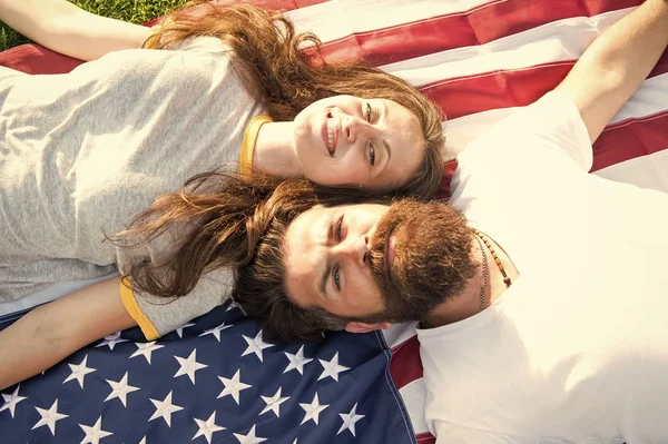 Pareja americana relajándose en la bandera de Estados Unidos al aire libre. Día de la Independencia. Fiesta nacional. hipster barbudo y chica enamorada. 4 de julio. Tradición americana. Historia de América. Personas patrióticas americanas — Foto de Stock