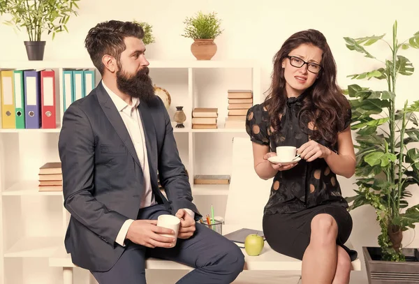 Couple coworkers relax coffee break. Share coffee with with colleague. Flirting colleagues. Bearded man and attractive woman. Man and woman conversation coffee time. Office coffee. Office rumors