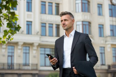 confident man formal outfit. modern life concept. businessman on way to office. agile business. use phone while walking. urban style and everyday life. ordinary working day. charismatic man in suit