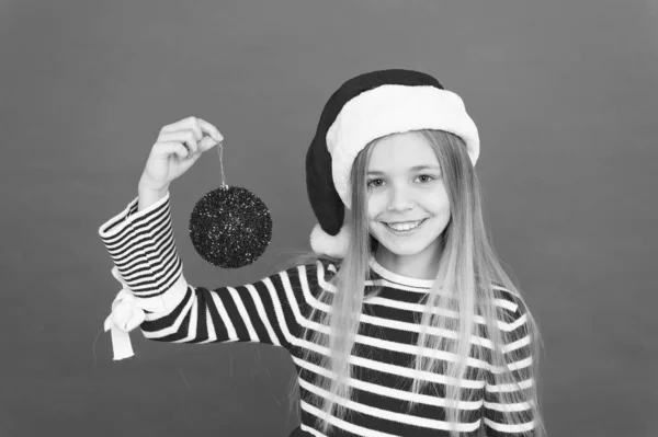 Decorare il Natale con gioia. Bambina Santa tenere palla albero di Natale. Sorriso felice bambino con pallina rossa glitter. Bauble di Natale o ornamento palla. Fragile decorazione a sfera di vetro. Lampadina di Natale o bauble — Foto Stock