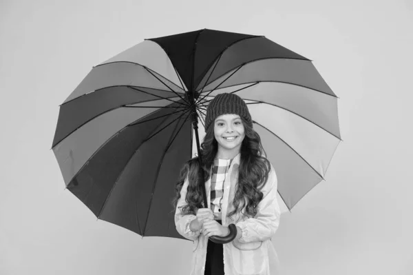 El paraguas no puede detener la lluvia. Feliz niño pequeño en impermeable llevar paraguas contra la lluvia. Linda colegiala esconderse bajo el paraguas en el clima lluvioso. La hace estar de pie bajo la lluvia — Foto de Stock