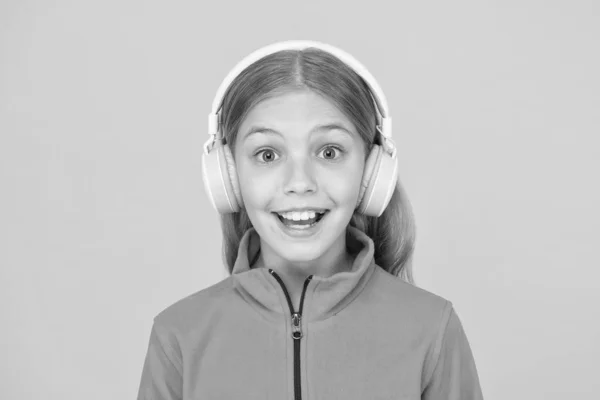 La canción feliz la hace sonreír. Niña feliz escuchar música sobre fondo amarillo. Pequeño niño disfruta de la canción jugando en los auriculares. Sonríe en la cara feliz. La música tiene emociones felices — Foto de Stock