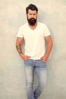 Kişisel stil. Fiziksel çekicilik. Yakışıklı hippi pantolonu. Erkek moda trendleri. Basit ve sıradan bir yaz. Acımasız maço gri arka plan. Erkek şiddeti. Sakallı adam erkeklik saçıyor.