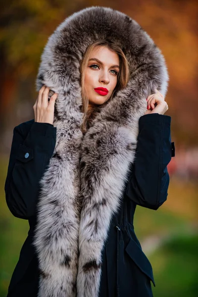 Fake fur fabric. Elegant girl walk in autumn park. Fur garments. Really warm and cozy. Expensive clothes. Luxury segment brand. Luxury fur. Beauty and fashion. Woman wear coat with huge furry hood