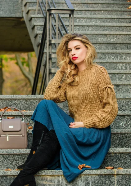Hogyan stílus pulóver és szoknya kombináció ősszel. Gyönyörű frizurájú nő ül a lépcsőn a szabadban. Őszi divat trend. Rétegtúlméretezett, lányos szoknya fölé kötött. Viselhető trendek. Őszi felszerelés képlet — Stock Fotó