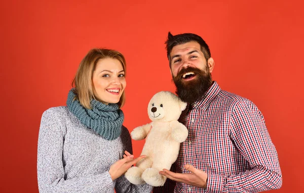 Couple in love holds teddy bear on red background.