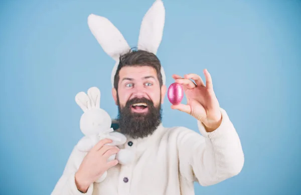 Декорування яєць на Великдень. Бородатий чоловік з іграшкою кролика та пасхальним яйцем. Гіпстер з довгими вухами кролика, що тримають заєць для відкладання яєць. Святкування весняних свят. Пасхальний кролик з кольоровими яйцями — стокове фото