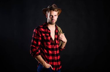 Vahşi batı ısınıyor. Vahşi batı rodeosu. Siyah şapkalı adam. Çiftlikte kareli gömlek. Klasik tarz adam. Vahşi Batı eski kovboy. Kement ipli bir kovboy. Batı. Batı kovboy portresi