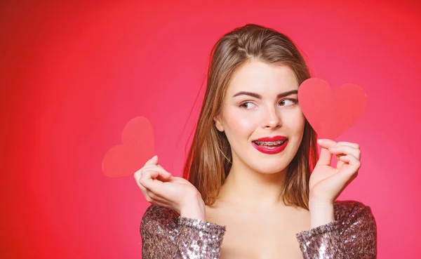 Les lèvres rouges maquillage femme tiennent coeur symbole amour. Concept de Saint Valentin. Braces et beauté. Sortir ensemble quand vous avez des appareils pour adultes. Jolie fille portant des appareils orthodontiques et souriant. Comment embrasser avec des bretelles — Photo