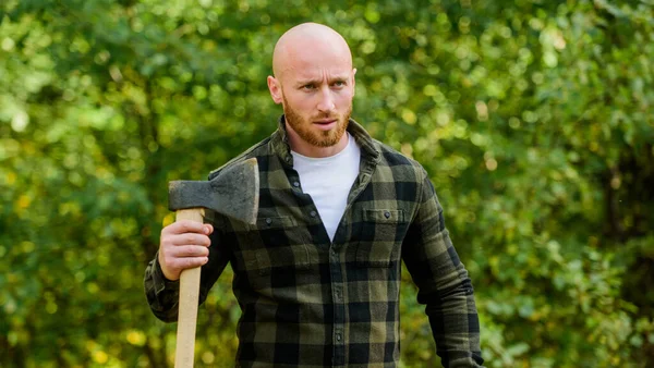 Determinación del espíritu humano. Hombre camisa a cuadros utilizar hacha. Brutal macho en el bosque. Potencia y fuerza. El leñador lleva hacha. Un leñador calvo. Cosecha leña. Caminata de vacaciones. Caminata en el bosque. Cuidado del bosque —  Fotos de Stock