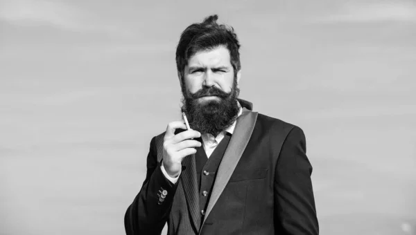 Fumo bello. brutale hipster caucasico con i baffi. hipster maturo con fumo di barba. Successo futuro. Moda formale maschile. Uomo barbuto che fuma sigarette. Uomo d'affari contro il cielo — Foto Stock