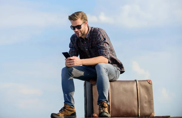 Schöner Reisender. Mann im Freien mit Vintage-Koffer. Transporteinrichtungen. Taxi rufen. Reisebüro. Reisen mit Gepäck. Reiseblogger. Mann sitzt vor Reise auf Koffer Gepäckkonzept — Stockfoto