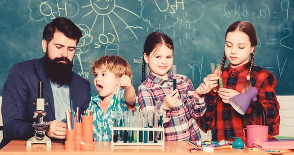Little kids learning chemistry in school laboratory. school kids scientist studying science. happy children teacher. back to school. students doing science experiments with microscope in lab