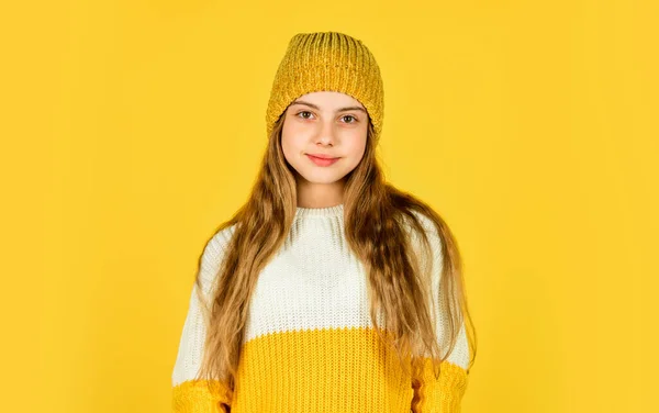 En liten flicka i stickade kläder. Skönhet och mode. bli varm under vintersäsongen. kall väderprognos. Glad barn bära hatt och favorit tröja. barndoms lycka. tonåring flicka gul bakgrund — Stockfoto