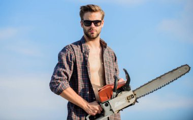 Tehlikeli işler bunlar. Erkekler vahşet ve cinsellik. Gerçek erkekler için bir iş. Erkek elektrikli testere. Her şeyi düzeltti. Güvenilir işçi. Erkeklerin gücü. Maço adam elektrikli testere aleti. seksi erkek gökyüzü arkaplanı