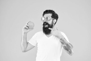 Sulu meyveler. Yaz beslenmesi. Yaz havasında sakallı hipster. Sarı arka planda turuncu güneş gözlüklü adam sakallı hipster. Olgun meyveli neşeli adam. Yaz tatili. Taze ve sağlıklı