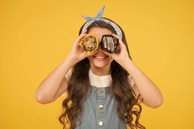 Mutlu çocukluk. Sarı arka planda cupcakes ile sevimli gülümseyen çocuk. Birine şekerle davran. Nefis çörekler. Fırın şekerleme konsepti. Çocuk kız sırlı kek tutar. Lezzetli cupcakes