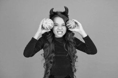 Eğleniyorum. Sonbahar tatili. Balkabaklarının geleneksel güz tatili özelliği. Tatil için dekorasyon. Oyuncu küçük şeytan. Boynuzlu kız balkabaklarıyla oynuyor. İyi tatiller. Tatlı çocuk Cadılar Bayramı 'nı kutluyor